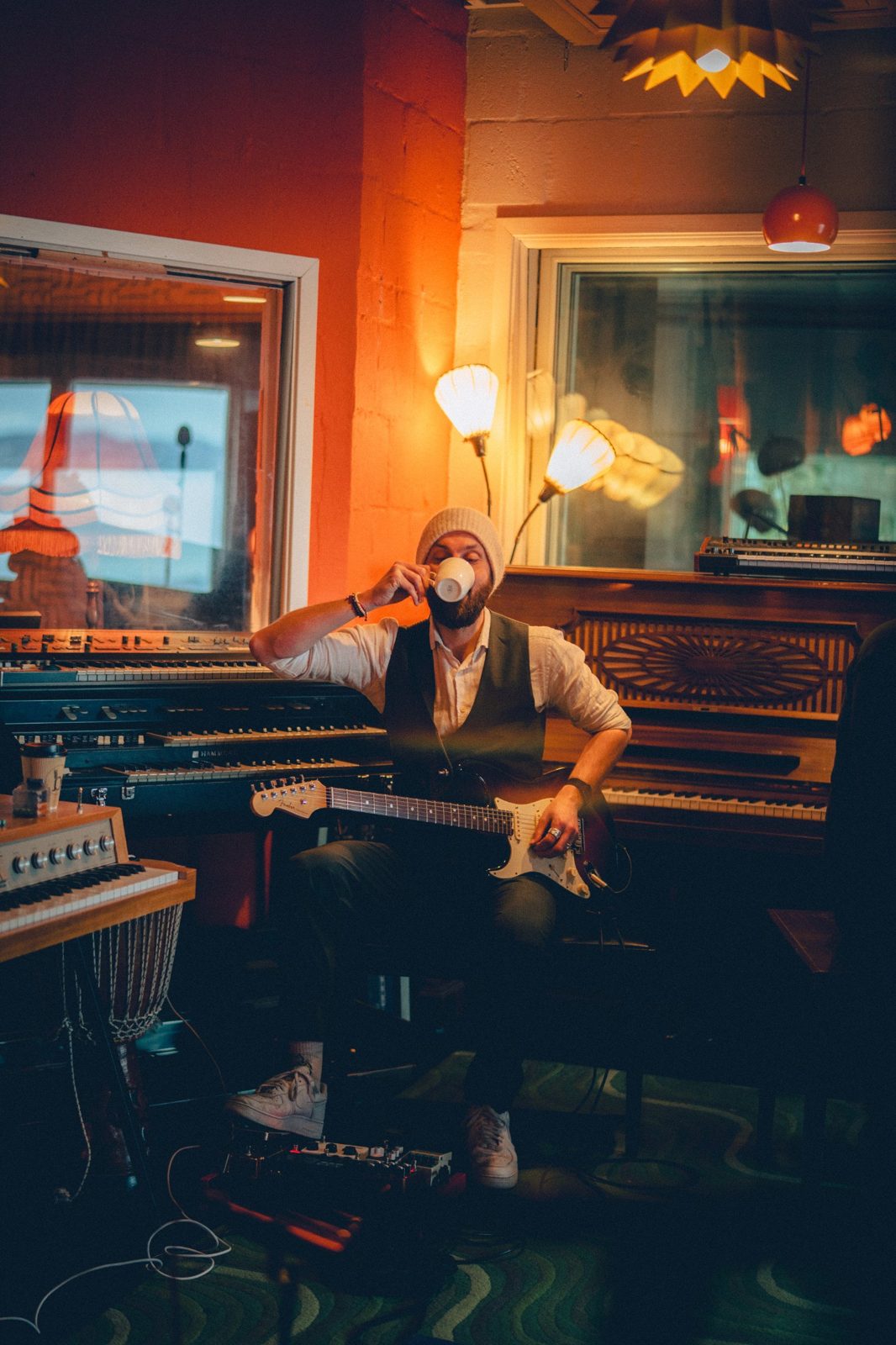 Martin Meneilly med gitar i et varmt studio med piano og orgel